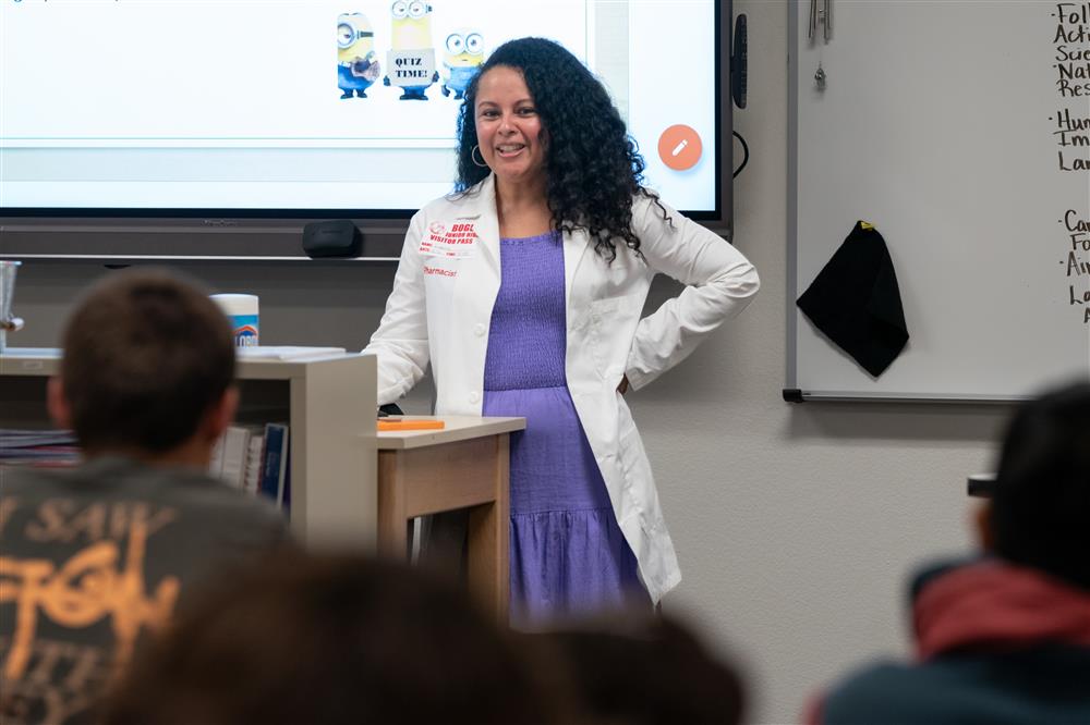 A photo of a pharmacist talking to a classroom of eighth graders.